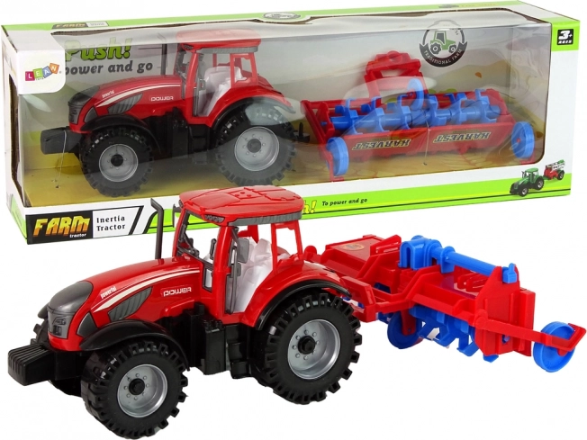 Červený traktor s pluhem s třecím pohonem
