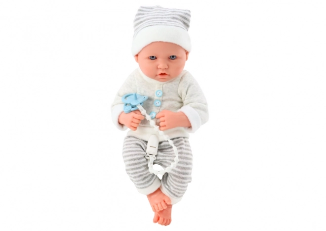Lifelike baby doll v bílo-šedém oblečku s čepičkou a dudlíkem