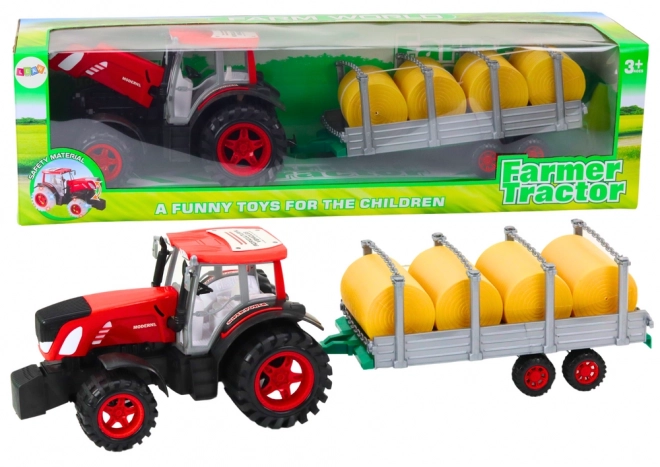 Velký traktor s přívěsem a balíky sena