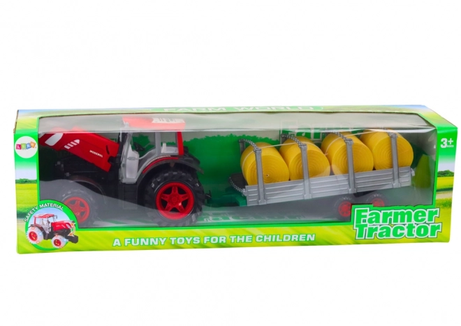 Velký traktor s přívěsem a balíky sena