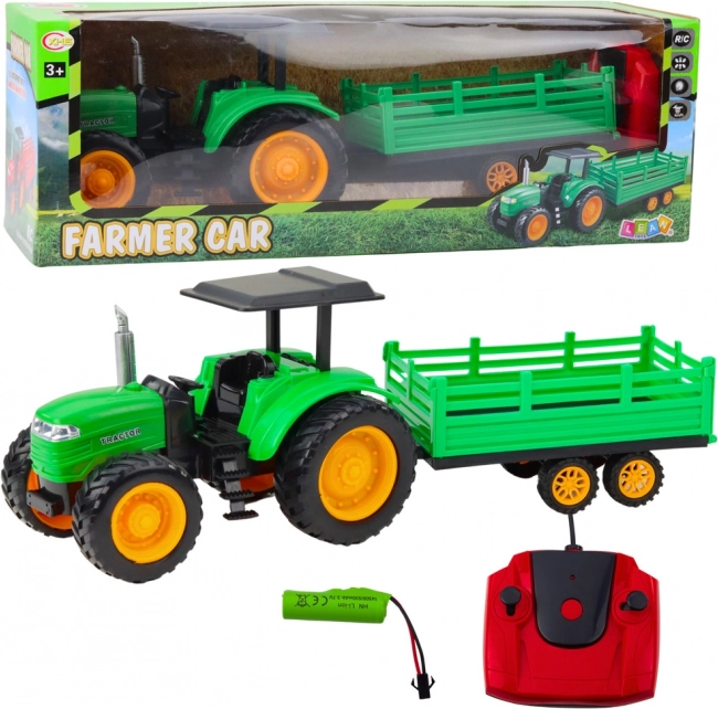 Zelený zdalně řízený farmářský traktor s přívěsem